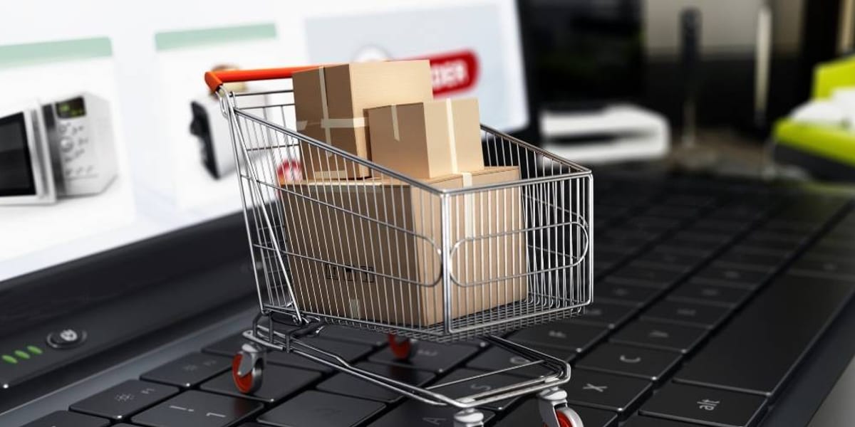 A miniature shopping trolley full of parcels sitting on a laptop keyboard